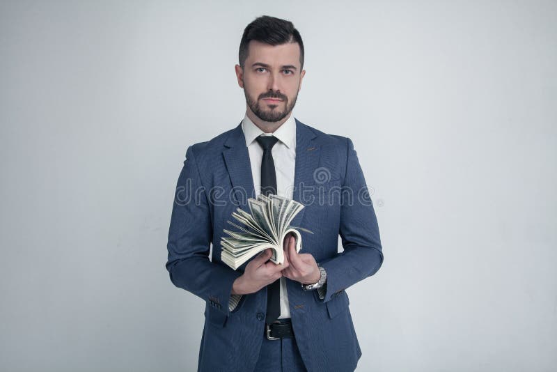 Um homem de negócios sério conta o dinheiro vestido em um terno e em olhares da forma na câmera Ganhou a loteria em um branco imagem de stock Um homem de negócios sério conta o dinheiro vestido em um terno e em olhares da forma na câmera Ganhou a loteria em um branco imagem de stock