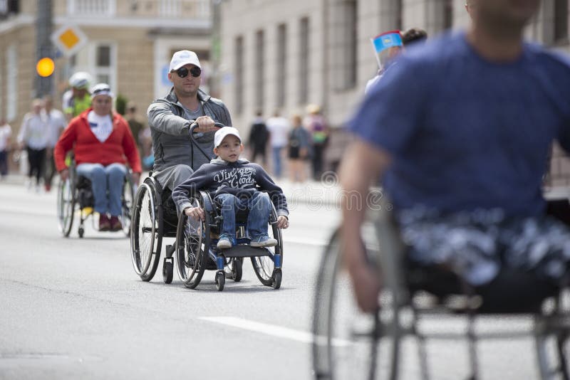 Um homem e uma criança numa cadeira de rodas competem numa maratona
