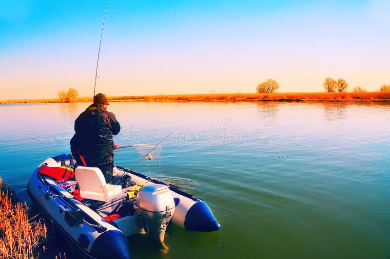Um homem está pescando com um barco inflável no rio imagem de stock royalty free Um homem está pescando com um barco inflável no rio imagem de stock royalty free