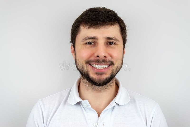 Um homem farpado considerável feliz mesmo de sorriso com olhos marrons em um t-shirt branco imagens de stock Um homem farpado considerável feliz mesmo de sorriso com olhos marrons em um t-shirt branco imagens de stock