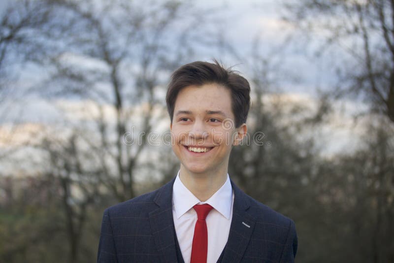 Um homem novo, um adolescente, em um terno clássico Passeio ao longo das avenidas do parque da mola imagem de stock royalty free Um homem novo, um adolescente, em um terno clássico Passeio ao longo das avenidas do parque da mola imagem de stock royalty free