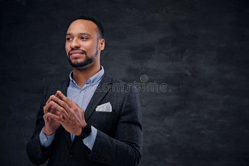 Um homem preto à moda vestiu-se em um terno sobre o fundo cinzento fotografia de stock Um homem preto à moda vestiu-se em um terno sobre o fundo cinzento fotografia de stock