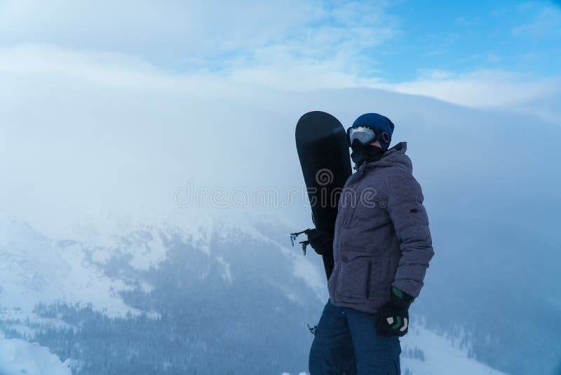 Um homem que guarda um snowboard à disposição Snowboarder nas montanhas imagens de stock Um homem que guarda um snowboard à disposição Snowboarder nas montanhas imagens de stock