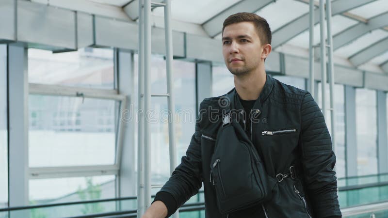 Um homem seguro novo com uma bolsa no terminal de aeroporto moderno