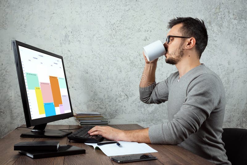 Um homem, um homem senta-se em uma tabela no escritório e no café das bebidas, uma ruptura Conceito para o trabalho de escritório imagem de stock Um homem, um homem senta-se em uma tabela no escritório e no café das bebidas, uma ruptura Conceito para o trabalho de escritório imagem de stock
