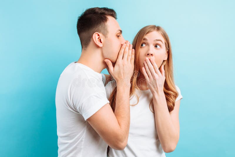 Um homem sussurra em sua orelha a uma mulher, dizendo seu algo secreto, chocante fotografia de stock Um homem sussurra em sua orelha a uma mulher, dizendo seu algo secreto, chocante fotografia de stock