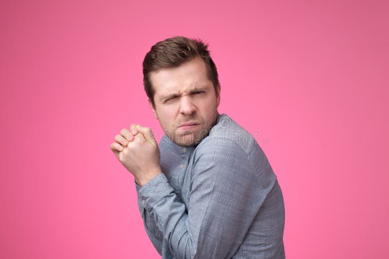 Um homem ávido novo esconde algo em suas mãos e olha cuidadosamente para a frente imagens de stock Um homem ávido novo esconde algo em suas mãos e olha cuidadosamente para a frente imagens de stock