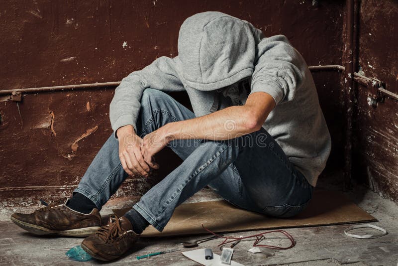 Um homem é um viciado em drogas com uma seringa usando drogas deitadas no f fotos de stock Um homem é um viciado em drogas com uma seringa usando drogas deitadas no f fotos de stock