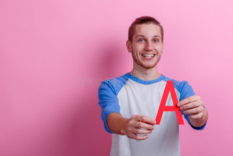 Um indivíduo alegre que guarda uma letra vermelha A Fundo cor-de-rosa imagens de stock Um indivíduo alegre que guarda uma letra vermelha A Fundo cor-de-rosa imagens de stock