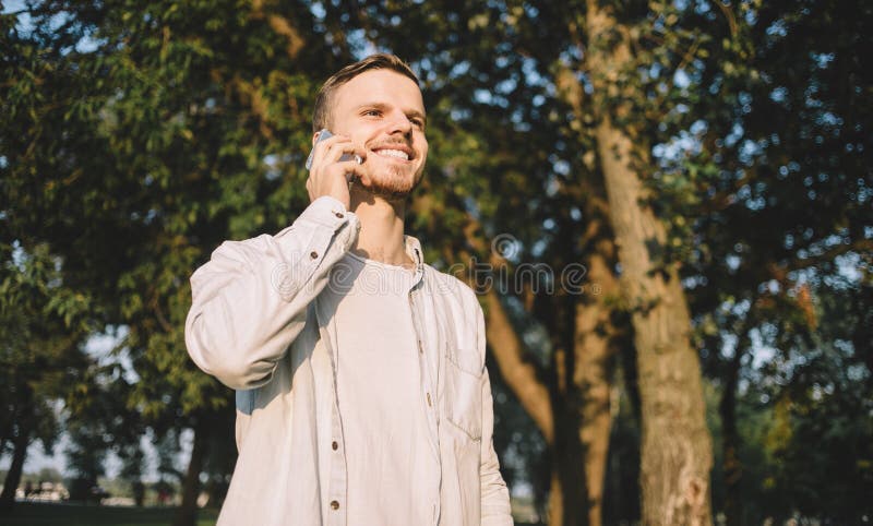 Um indivíduo com um telefone no parque imagens de stock Um indivíduo com um telefone no parque imagens de stock