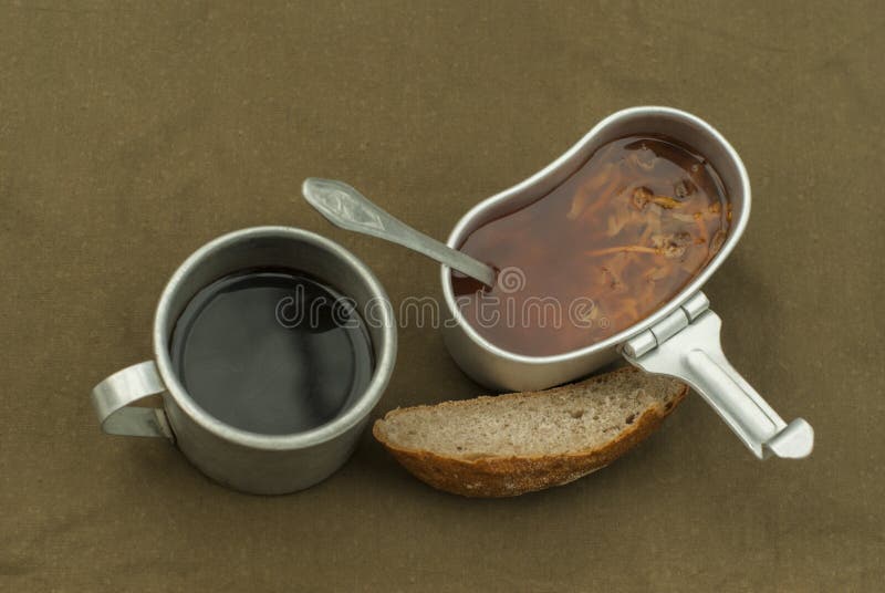 A scanty road meal: soup in a mess tin, cooled coffee in a vintage army mug, and a loaf of bread on a spread tarpaulin. A scanty road meal: soup in a mess tin, cooled coffee in a vintage army mug, and a loaf of bread on a spread tarpaulin