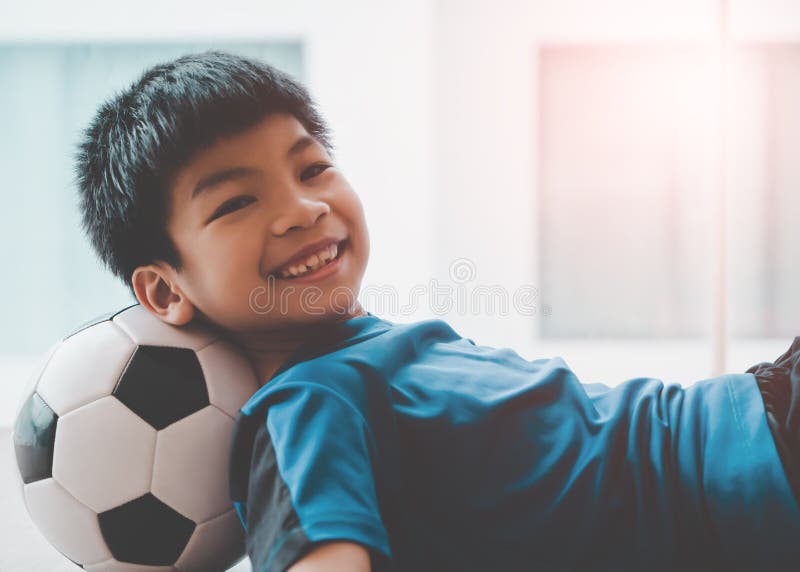 Menino Do Jogador De Futebol Que Pisa Na Bola Na Sala Imagem de