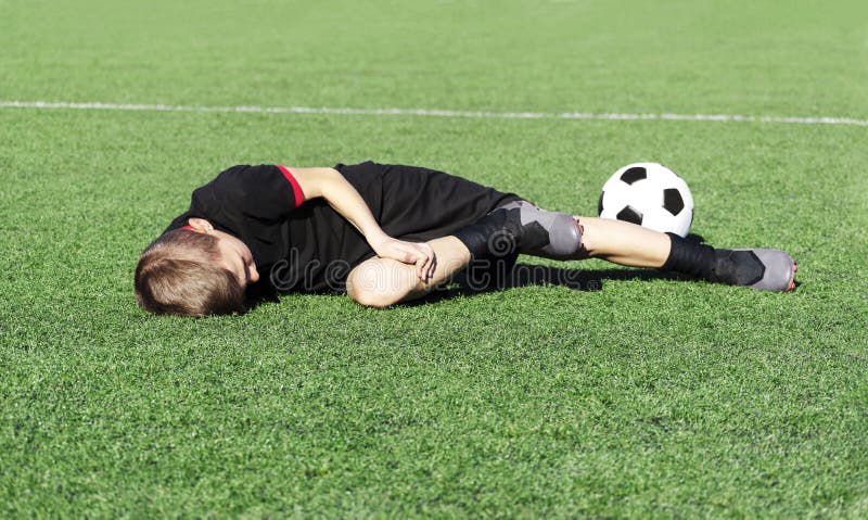 Um Jovem Jogador De Futebol Machucou Sua Perna Durante O Jogo E Bola No  Campo. Lesão Infantil No Conceito Desportivo. Cópia Foto de Stock - Imagem  de joelho, futebolista: 176890416