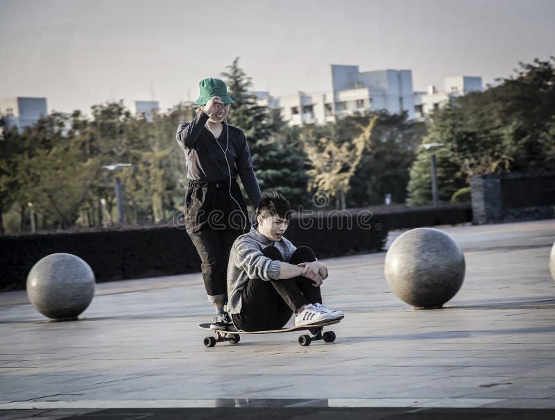 Um menino e uma menina que patinam em um único skate fotografia de stock royalty free Um menino e uma menina que patinam em um único skate fotografia de stock royalty free