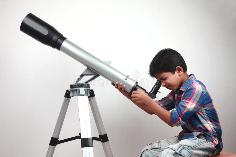 Um menino olha através de um telescópio