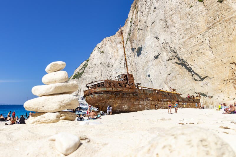 Um monte de pedras é ficado situado na frente da destruição do navio na praia de Navagio na ilha de Zakynthos, Grécia fotos de stock royalty free Um monte de pedras é ficado situado na frente da destruição do navio na praia de Navagio na ilha de Zakynthos, Grécia fotos de stock royalty free