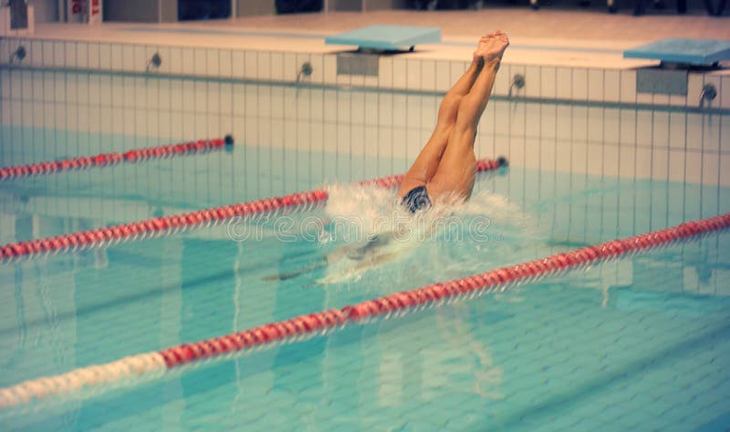 Um nadador fêmea, esse salto e mergulho na piscina do esporte interno Mulher desportiva fotos de stock Um nadador fêmea, esse salto e mergulho na piscina do esporte interno Mulher desportiva fotos de stock