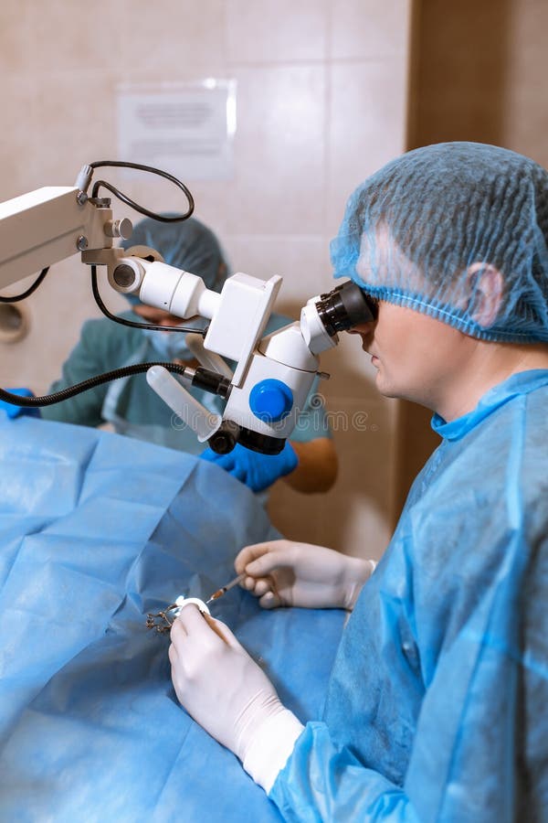Um oftalmologista profissional executa a cirurgia do olho com um microsc?pio O doutor introduziu o dilatador no olho, lavagens e foto de stock royalty free Um oftalmologista profissional executa a cirurgia do olho com um microsc?pio O doutor introduziu o dilatador no olho, lavagens e foto de stock royalty free