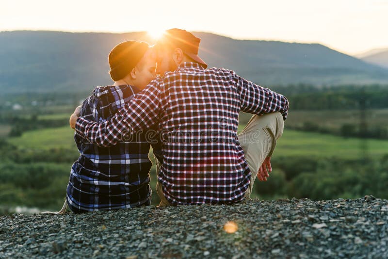 Um par novo no amor é inclinação assentada entre si na parte superior da montanha no por do sol Pares delicados em imagens de stock royalty free Um par novo no amor é inclinação assentada entre si na parte superior da montanha no por do sol Pares delicados em imagens de stock royalty free