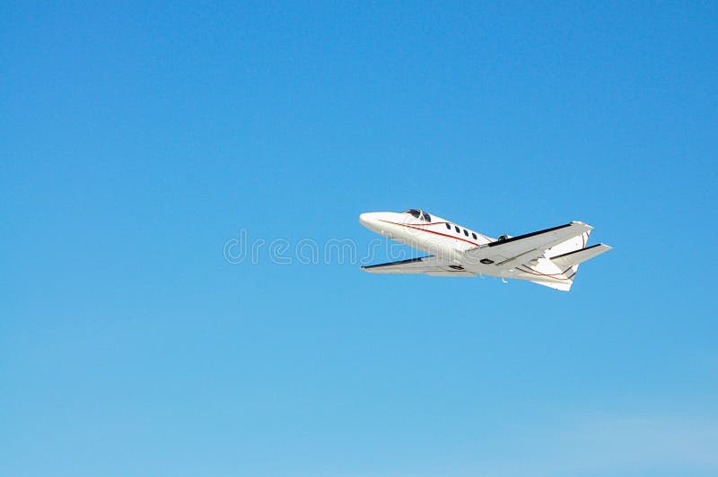 Um plano privado branco voa no céu azul foto de stock Um plano privado branco voa no céu azul foto de stock