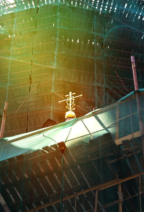Um raio de luz na cruz de uma igreja ortodoxa durante o tempo de reparo imagem de stock Um raio de luz na cruz de uma igreja ortodoxa durante o tempo de reparo imagem de stock