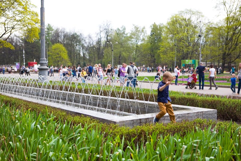 Um rapaz pequeno está saltando ao lado de uma fonte no parque de Sokolniki foto de stock Um rapaz pequeno está saltando ao lado de uma fonte no parque de Sokolniki foto de stock