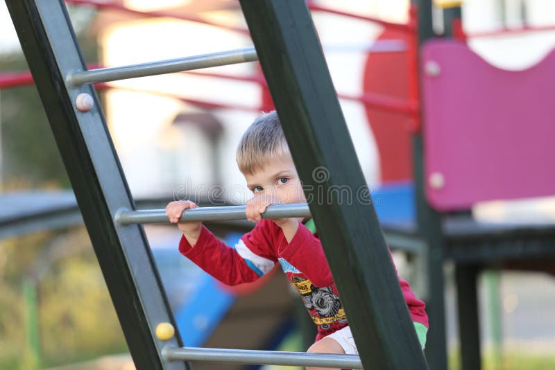 Um rapaz pequeno que joga em um campo de jogos fotografia de stock