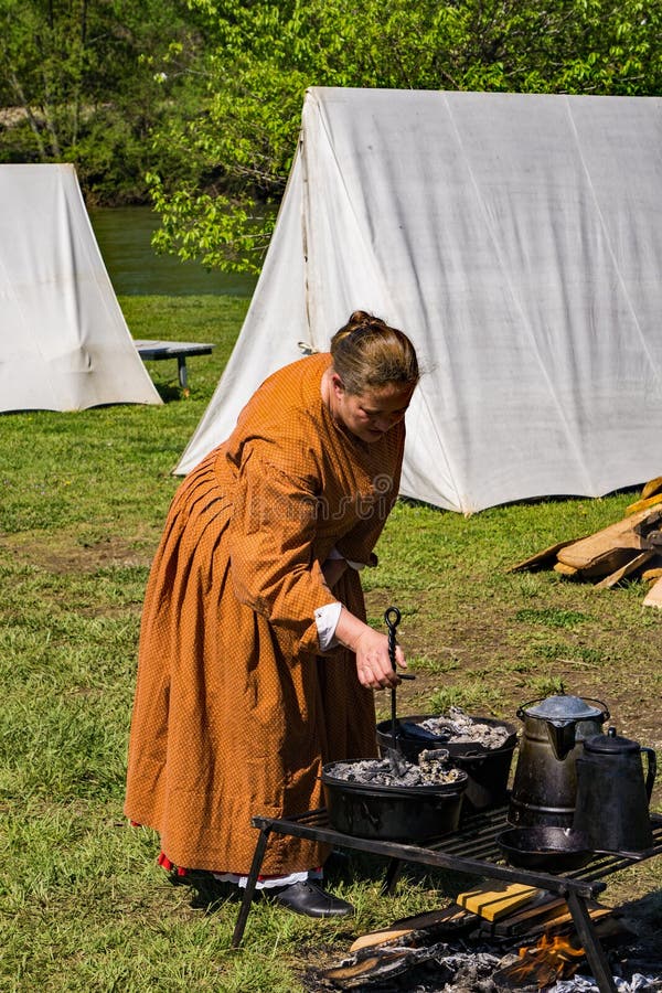 Um Reenactor fêmea que cozinha no acampamento confederado imagens de stock Um Reenactor fêmea que cozinha no acampamento confederado imagens de stock