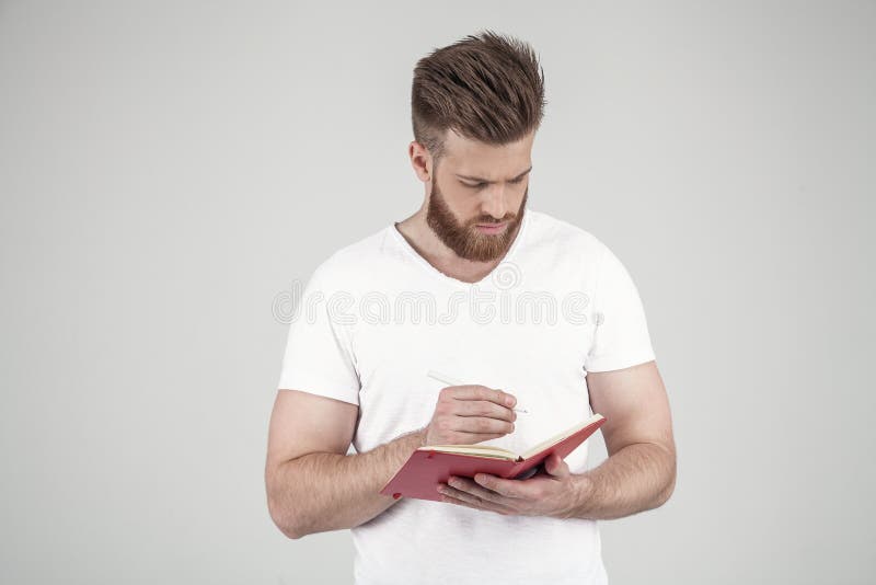 Um retrato de um homem bonito com uma barba e um penteado elegante vestidos na roupa ocasional grava pensativamente seus pensamen fotos de stock royalty free Um retrato de um homem bonito com uma barba e um penteado elegante vestidos na roupa ocasional grava pensativamente seus pensamen fotos de stock royalty free