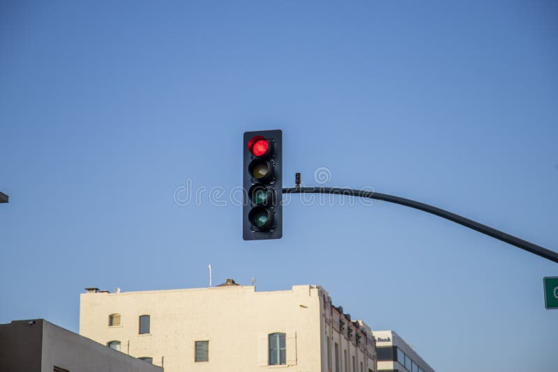 A traffic signal with 4 lights with the red light on surrounded by white buildings and clear blue sky in Pasadena California USA. A traffic signal with 4 lights with the red light on surrounded by white buildings and clear blue sky in Pasadena California USA