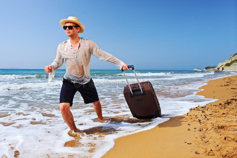 Um turista que carreg uma mala de viagem na praia