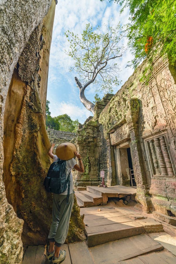 Um turista que visita ruínas de Angkor entre a selva, complexo do templo de Angkor Wat, destino Camboja do curso Mulher com chap fotos de stock royalty free Um turista que visita ruínas de Angkor entre a selva, complexo do templo de Angkor Wat, destino Camboja do curso Mulher com chap fotos de stock royalty free