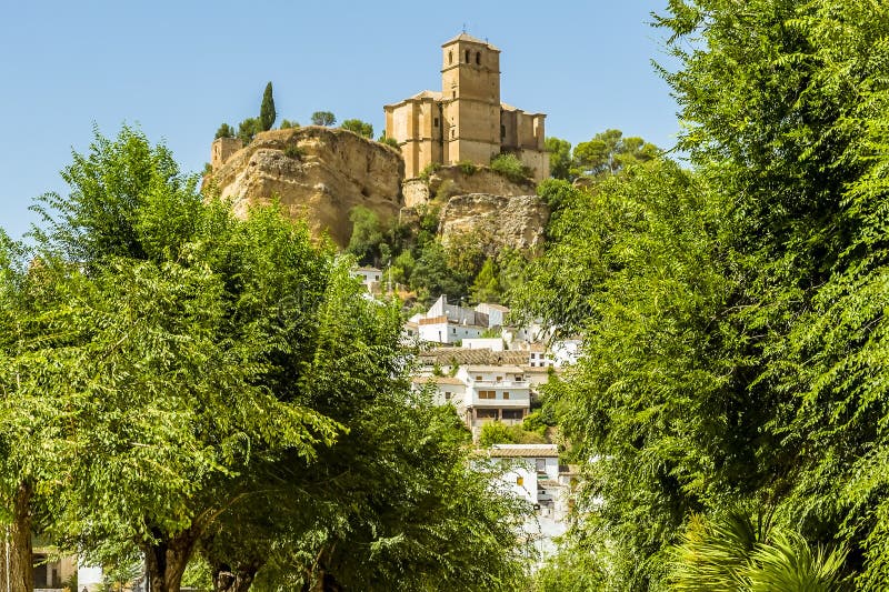 A glimpse of the hilltop fortress in the town of Montefrio, Spain viewed through a gap in the trees in the summertime. A glimpse of the hilltop fortress in the town of Montefrio, Spain viewed through a gap in the trees in the summertime