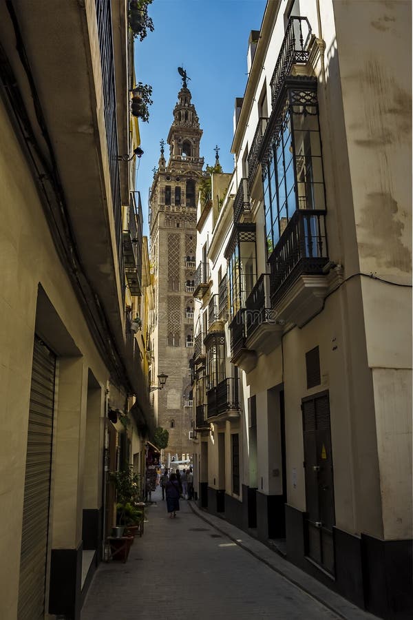 A glimpse down a street in Seville, Spain towards the tower of the cathedral of St Mary in the summertime. A glimpse down a street in Seville, Spain towards the tower of the cathedral of St Mary in the summertime