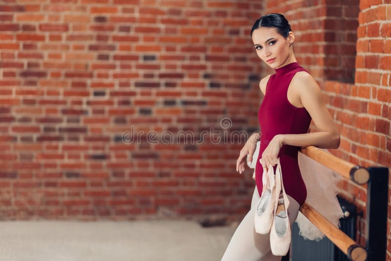 Uma bailarina nova magro bonita que guarda sapatas do pointe para dançar imagens de stock Uma bailarina nova magro bonita que guarda sapatas do pointe para dançar imagens de stock