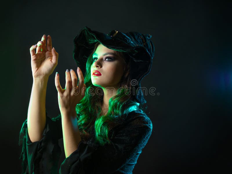 Uma Jovem Bruxa Bonita Em Um Chapéu Cônico Segura Uma Abóbora De Halloween  Em Suas Mãos E Faz Um Feitiço Com Sua Mão. Foto Royalty Free, Gravuras,  Imagens e Banco de fotografias.