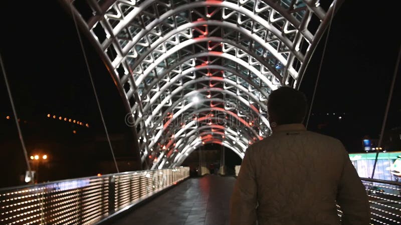 Uma caminhada do homem sobre ulluminating ilumina a ponte no movimento lento