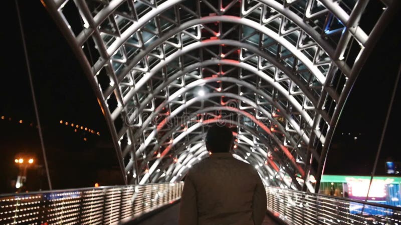 Uma caminhada do homem sobre ulluminating ilumina a ponte no movimento lento