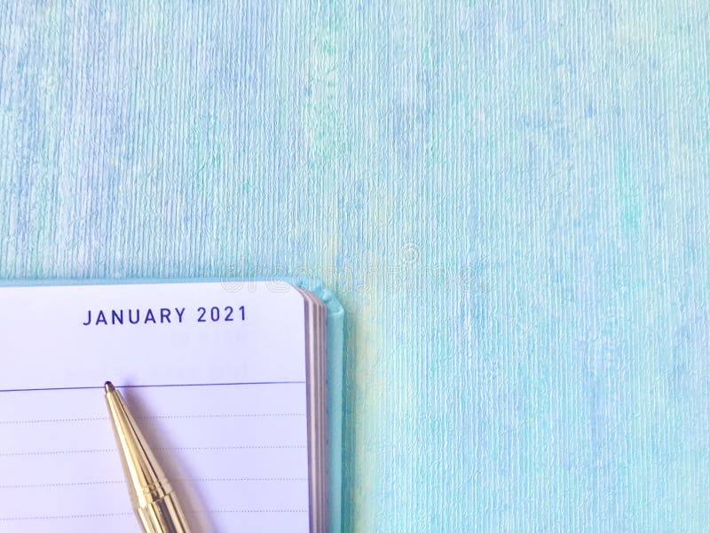 Uma caneta dourada que aponta para janeiro de 2021 no fundo azul-diário aberto.