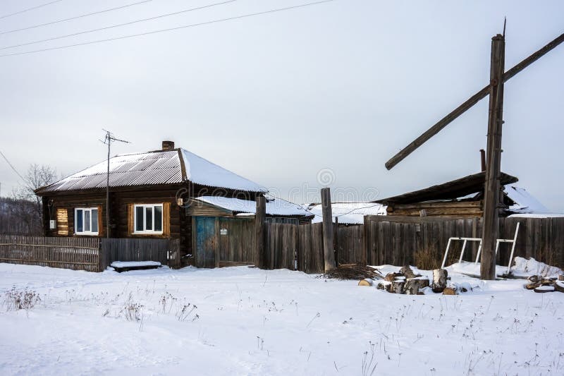 Uma casa ordinária de madeira em uma vila Siberian pequena na estação do inverno foto de stock Uma casa ordinária de madeira em uma vila Siberian pequena na estação do inverno foto de stock