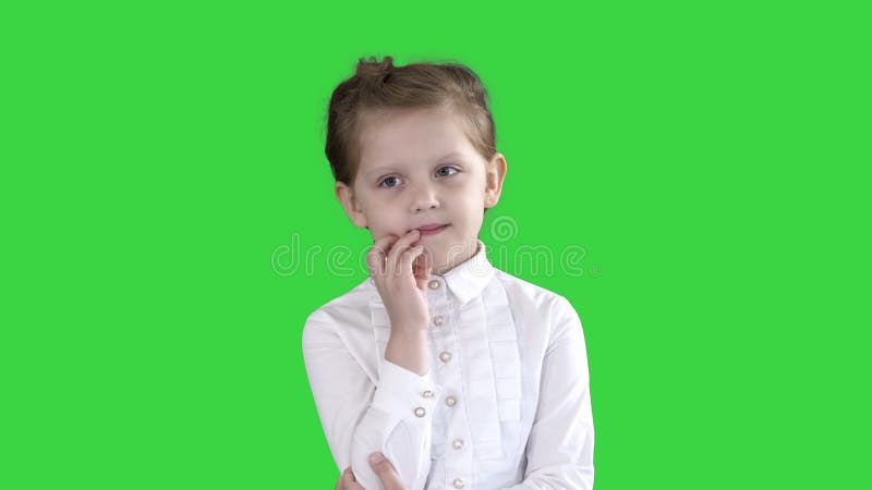 Uma curiosa garotinha se posiciona e pensa em uma tela verde, chave cromática