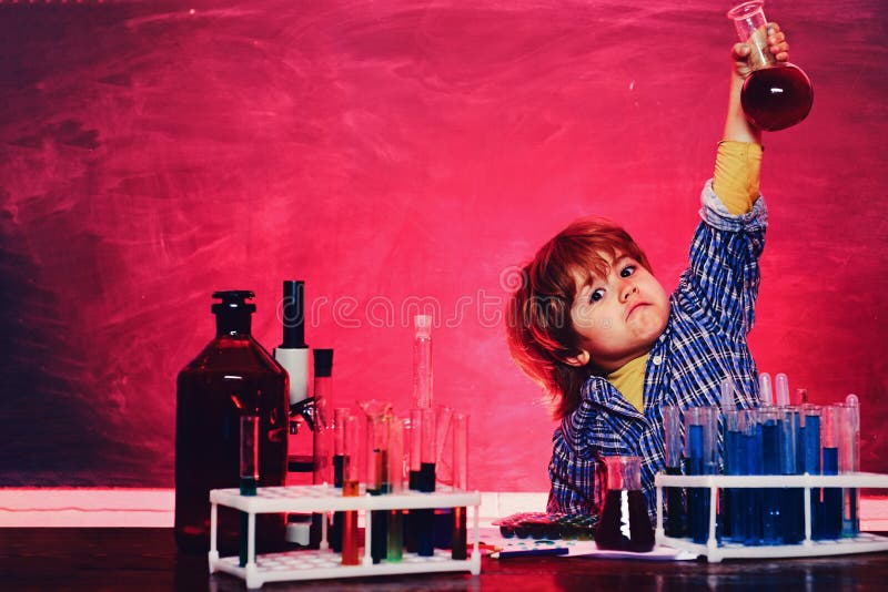 A chemistry demonstration. Cheerful smiling little boy having fun against blue wall. School chemistry lessons. Preschooler. What is taught in chemistry. A chemistry demonstration. Cheerful smiling little boy having fun against blue wall. School chemistry lessons. Preschooler. What is taught in chemistry.