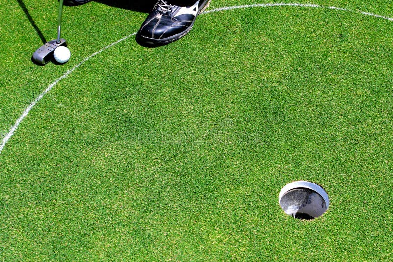 Uma esfera de golfe branca perto do furo foto de stock Uma esfera de golfe branca perto do furo foto de stock