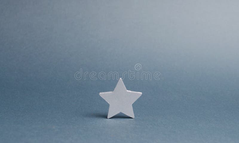 Uma estrela de prata em um fundo cinzento O conceito começou a maneira de negócio ao sucesso, as primeiras etapas O crescimento d fotografia de stock Uma estrela de prata em um fundo cinzento O conceito começou a maneira de negócio ao sucesso, as primeiras etapas O crescimento d fotografia de stock