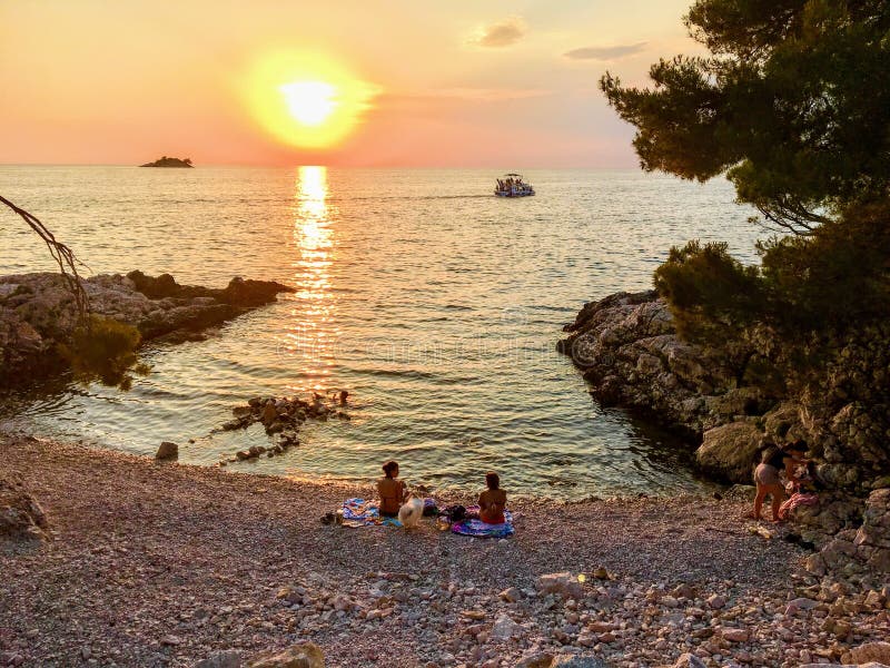 Uma família agradável dos locals que apreciam um por do sol bonito ao longo das costas do mar de adriático em Rovinj, Croácia em fotografia de stock royalty free Uma família agradável dos locals que apreciam um por do sol bonito ao longo das costas do mar de adriático em Rovinj, Croácia em fotografia de stock royalty free