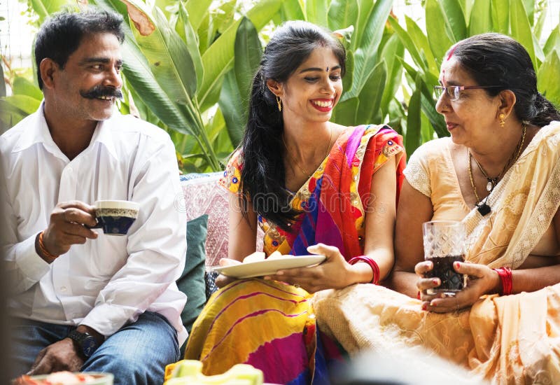 Uma família indiana feliz que come bebidas junto fotografia de stock Uma família indiana feliz que come bebidas junto fotografia de stock