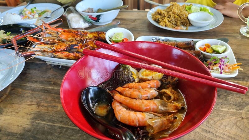 Uma farinha de frutos do mar vibrante que apresenta ramen de camarão num prato de arroz grelhado de prata vermelha imagem de stock