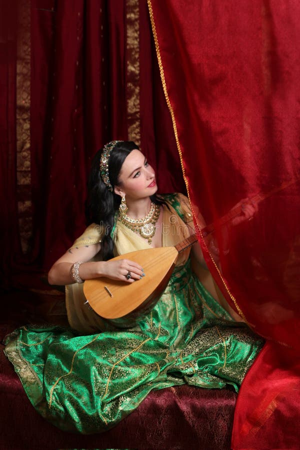 A girl in a Turkish Ottoman historical costume in the style of the magnificent century. a woman plays the national musical instrument baglama saz. A girl in a Turkish Ottoman historical costume in the style of the magnificent century. a woman plays the national musical instrument baglama saz