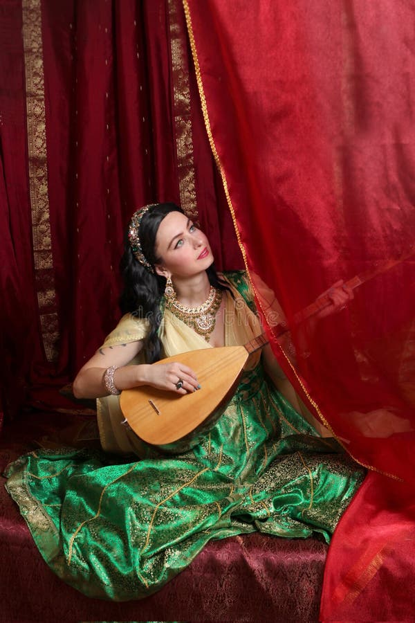 A girl in a Turkish Ottoman historical costume in the style of the magnificent century. a woman plays the national musical instrument baglama saz. A girl in a Turkish Ottoman historical costume in the style of the magnificent century. a woman plays the national musical instrument baglama saz