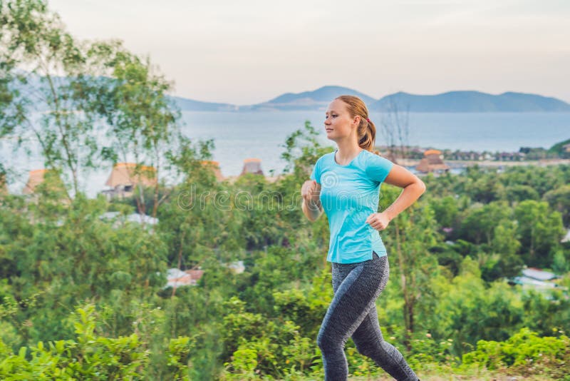 Uma jovem mulher desportivo é contratada na corrida contra o mar foto de stock Uma jovem mulher desportivo é contratada na corrida contra o mar foto de stock